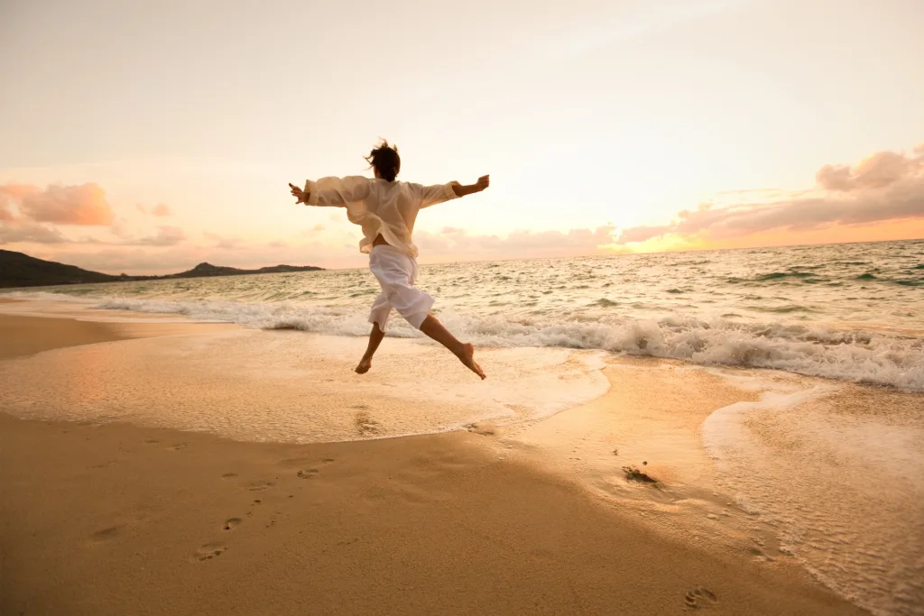 woman-on-beach jumping for JOMO